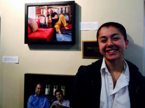 Shishi Shomloo '15 at her first photo gallery opening at Archer. Behind her are two examples of her work, one of which is of her and her father. Photographer: Haley Kerner '16