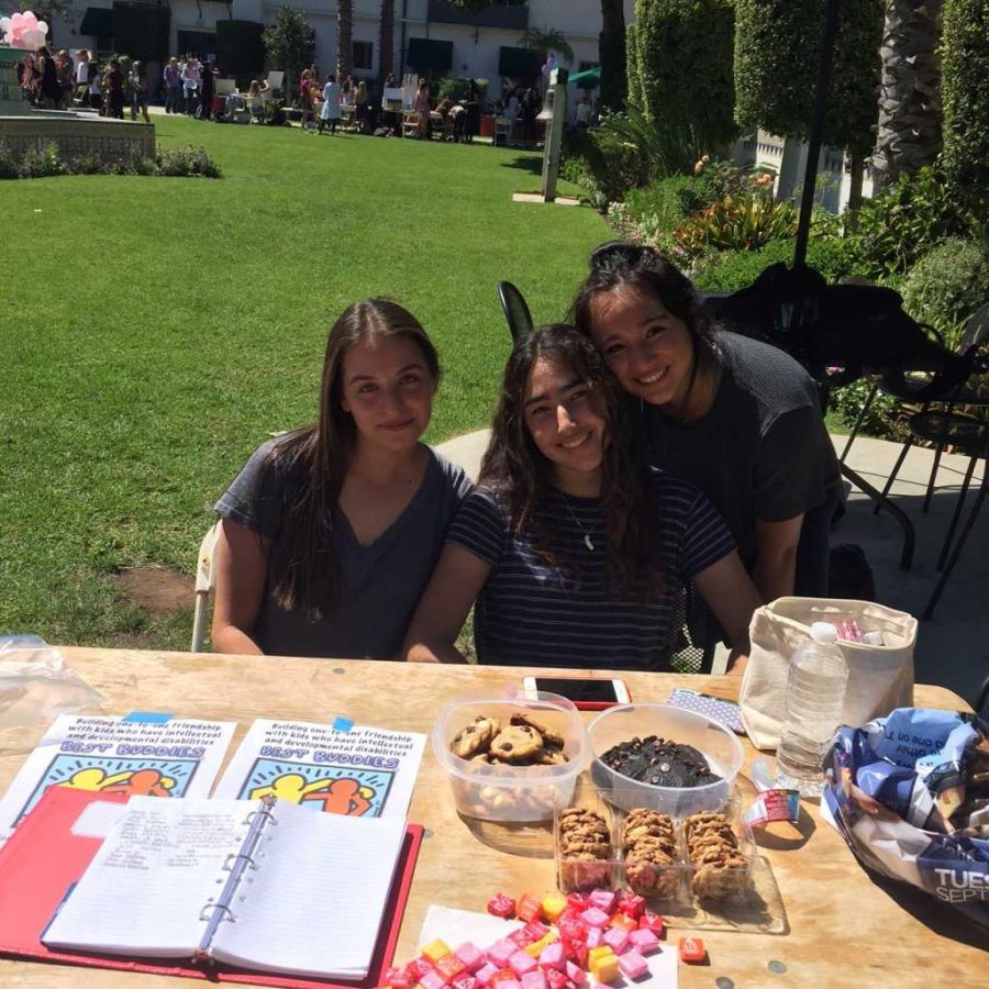 Students Ari Brown 16, Kimia Khatibi 16, and Seaf Hartley 16 pose behind the Best Buddies table full of treats at the Club Fair. Photo by Helena Heslov 16