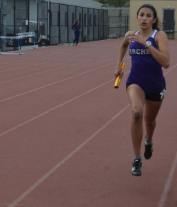 Namazie runs with a baton. At this meet, Namazie set two school records in the 800m and 1600m run. Image courtesy of Amelia Mathis.