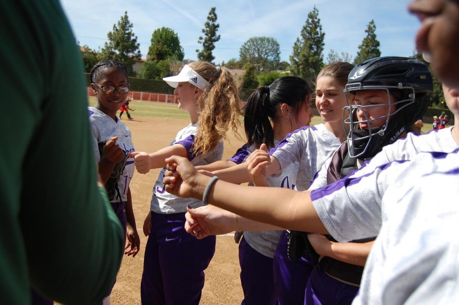 The varsity softball team huddles before a game. The team includes a diverse group of students and is a microcosm of Archers diversity.