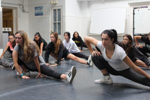 Meagan Rowles '18 (front left) and Cameron Thompson '18 (front right) stretch at the beginning of their first session with Jacob Guzman from "Hamilton." The upper school girls learned a dance to the song "The Room Where It Happened."