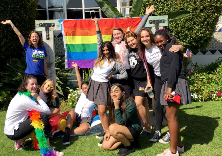 A group of juniors pose in front of the pride flag in the courtyard. Several of the girls, including Isabel Kuh, bottom left, helped organize the celebration.