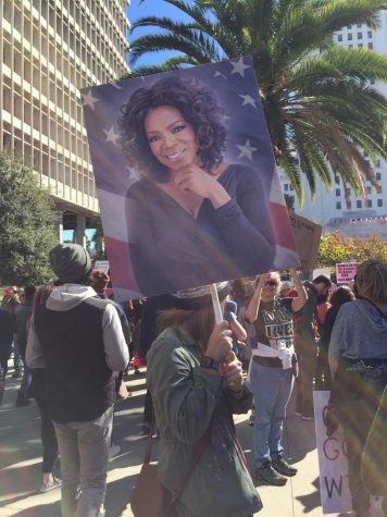 A woman holds a sign of Oprah Winfrey above her head, while listening to a speaker at the 2018 womens march in Los Angeles.  An estimated 500,000 people attended the march in Downtown LA.