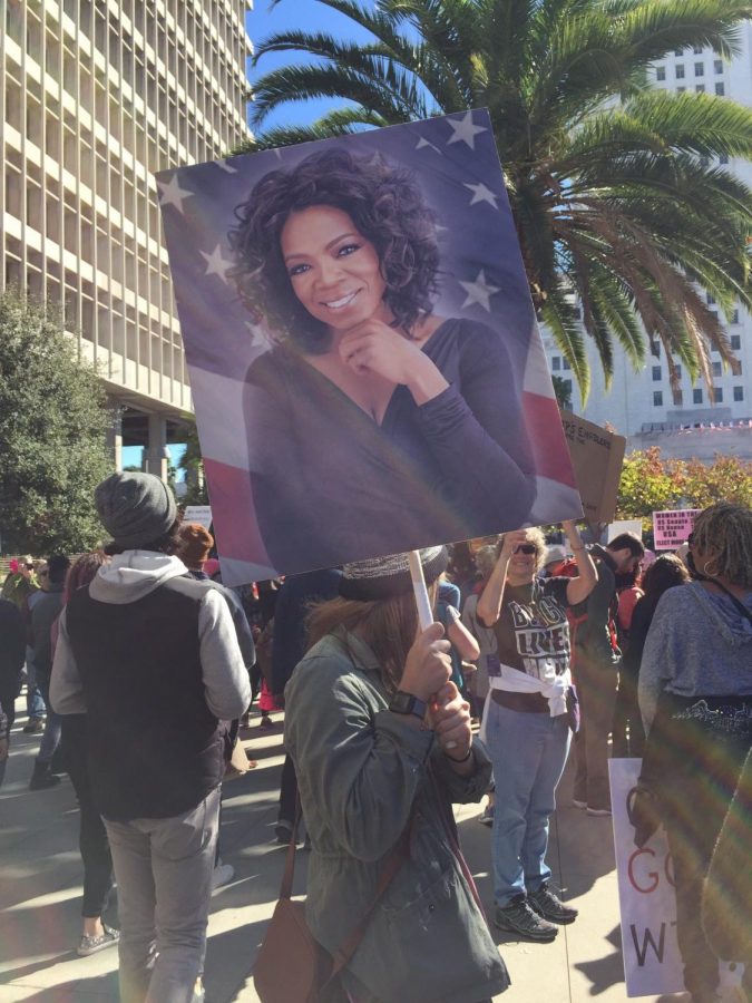 A woman holds a sign of Oprah Winfrey above her head, while listening to a speaker at the 2018 womens march in Los Angeles.  An estimated 500,000 people attended the march in Downtown LA.