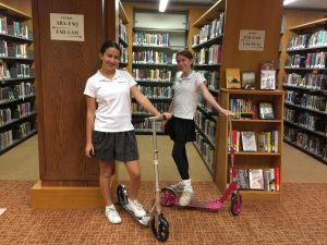 Jessica Tuchin 21 and Shainna Orecklin 21 pose for a picture with their scooters in the library.  Every morning, they drop their scooters off in the library to be stored for the day.