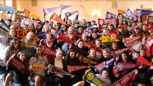 The Class of 2018 and Head of School Elizabeth English pose in the Rose Room with pennants. The seniors, along with Gwen Strasberg 19, participated in the pennant-hanging event.