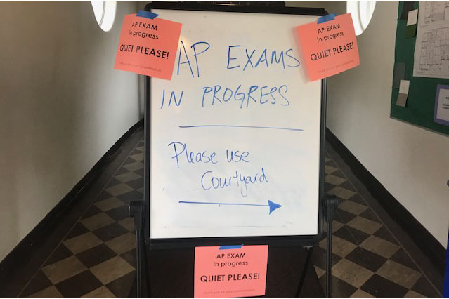 A sign in front of the Dining Hall, which was lined with chairs and individual desks  for students taking the AP Exams. The exams were held in other places such as the library and lighting studio.