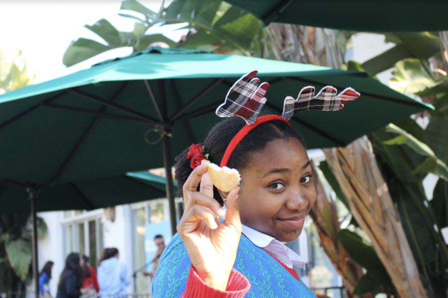 Sophomore Ruby Williams eats a sugar cookie she made at the cookie decorating station. This was one of the multiple stations spread out across the courtyard, including latkes and hot chocolate. 