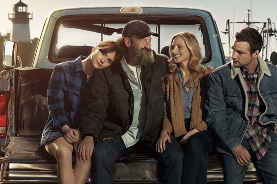The Rossi family; Ruby (Emilia Jones), Frank (Troy Kotsur), Jackie (Marlee Matlin) and Leo (Daniel Durant) sit on the back of a truck on a sunny day, highlighting their close-knit family relationships. CODA is a dramatic-comedy about Ruby, the only hearing member of her family, and the Rossis as Ruby is in her senior year of high school and contemplating her future.