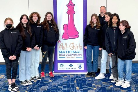The chess team and chess coach Jay Stallings stand in front of a poster advertising the tournament before competing in their first rounds of matches. At the tournament, each player earned at least one point by winning a match for the Archer chess team.
