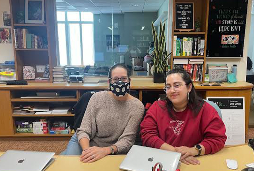 Librarians Jacque Giebel and Denise Hernandez sit in the library together during the school day. Giebel has chosen to wear a mask, and Hernandez decided to not wear one.