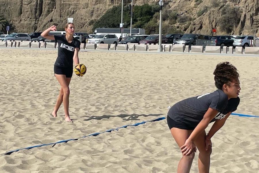 Elle Vandewhege (26) serves a ball at a beach volleyball scrimmage against Windward School. Her partner, Similce Diesel (26), was prepared to return the opponents ball.