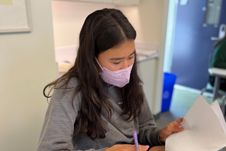 Junior Dani Fenster works on a homework sheet while wearing a mask in math teacher Matthew Barthas classroom. On May 4, the indoor mask mandate took effect once again due to the rising cases on campus.