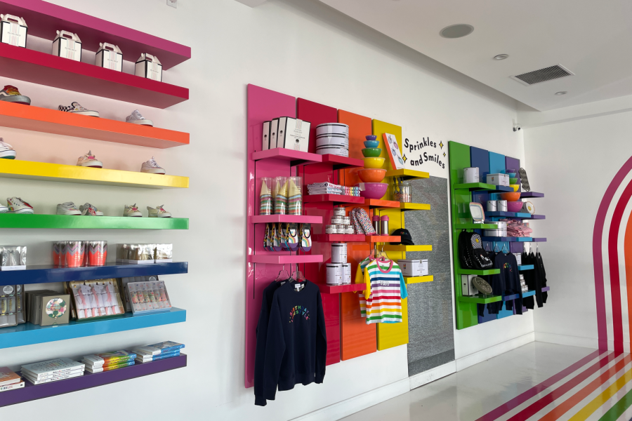 Flour Shops location in Beverly Hills, CA, displays their colorful merch wall, including clothes and baking supplies. The store originated in New York and expanded to Los Angeles in 2020.