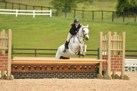 Evie Becky (28) and her horse, Snowflake, jump a height of 2 feet 9 inches at the Traverse City Horse Show on July 16, 2021. Becky has been riding for 5 years and competes in the equitation and hunter categories.