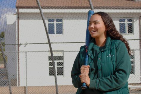 Junior Malia Apor holds up her softball bat on Archers softball field. Apor said she developed a love for the game when she first started playing more than 10 years ago. “[Softball] is a rock for me,” Apor said. “Its something I really enjoy, and it brings me a lot of happiness.”