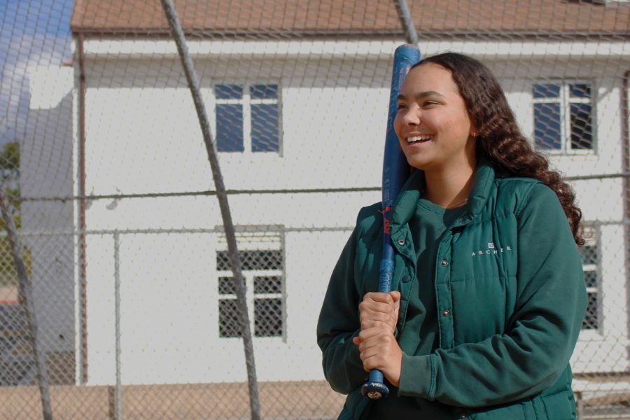 Junior Malia Apor holds up her softball bat on Archers softball field. Apor said she developed a love for the game when she first started playing more than 10 years ago. “[Softball] is a rock for me,” Apor said. “Its something I really enjoy, and it brings me a lot of happiness.”