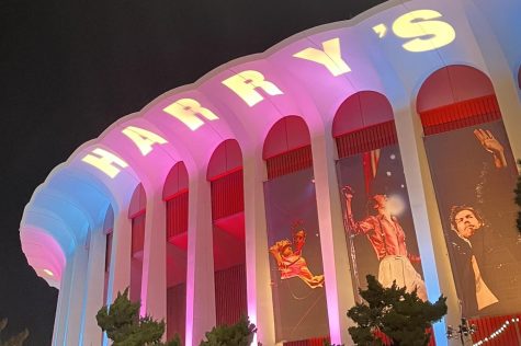 The Kia Forum was lit up in pink and blue in honor of Harry Styles fourteenth Los Angeles show. Styles sold out 15 nights in the Inglewood venue, and he played a 90-minute setlist to a sea of fans with colorful outfits and boas.