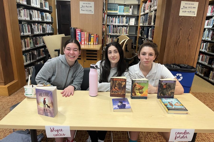 Sophomores Siena Ferraro, Mia Vosicher and Bryce Collis present their display of books they brought in for the used book fair. The fair took place in the library Friday, Feb. 17, during lunchtime.