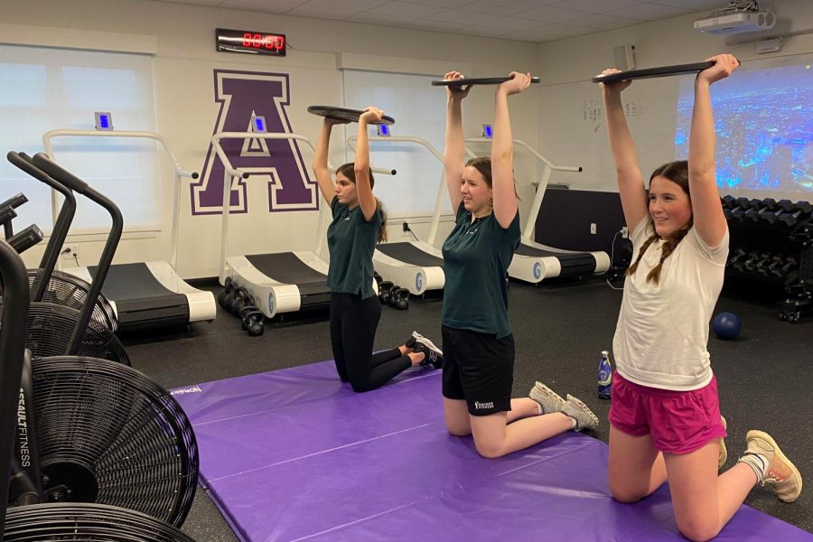 Lucine Stephan, Quinn Evans-Agard and Claire Doyle lift weights during varsity swim practice in the training center. The team practices five to six days a week, focusing on various skills and mindsets. This year, were focusing on standing tall, Head Coach Wilma Wong said. 