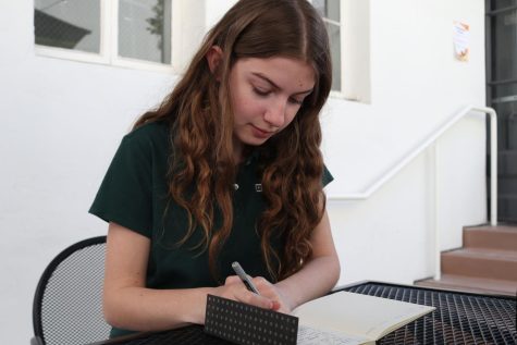 Freshman Vivi Arnold writes in her book-writing journal in the RBG courtyard. Arnold is writing her own fantasy novel entitled “Through the Years” about a time traveler and an immortal person that keep meeting each other and wonder why.