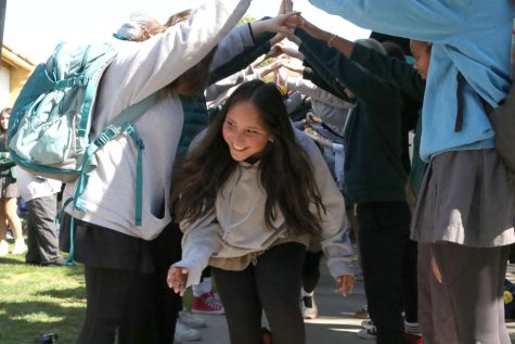 Seventh grader Andrea Fuentes runs through a human tunnel during the pep rally. Students gather in the courtyard on Mar. 3 to celebrate student athletes winter sports accomplishments.