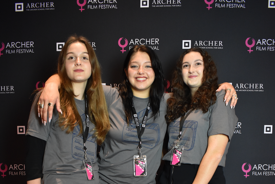 Festival board members Grace Whitney (’25), Sadie Long (’24) and Grace Delossa (’23) pose for a picture on the pink carpet during Archer’s Film Festival 2023. According to film teacher Andrew Ruiz, the board has gained many leadership skills over months of choosing films, booking the venue, organizing logistics and generating publicity for the event.