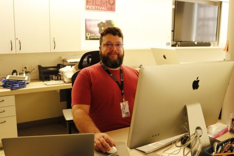 Andrew Ruiz sits at his desk in the media space. He is one of the new art teachers this year and teaches film.