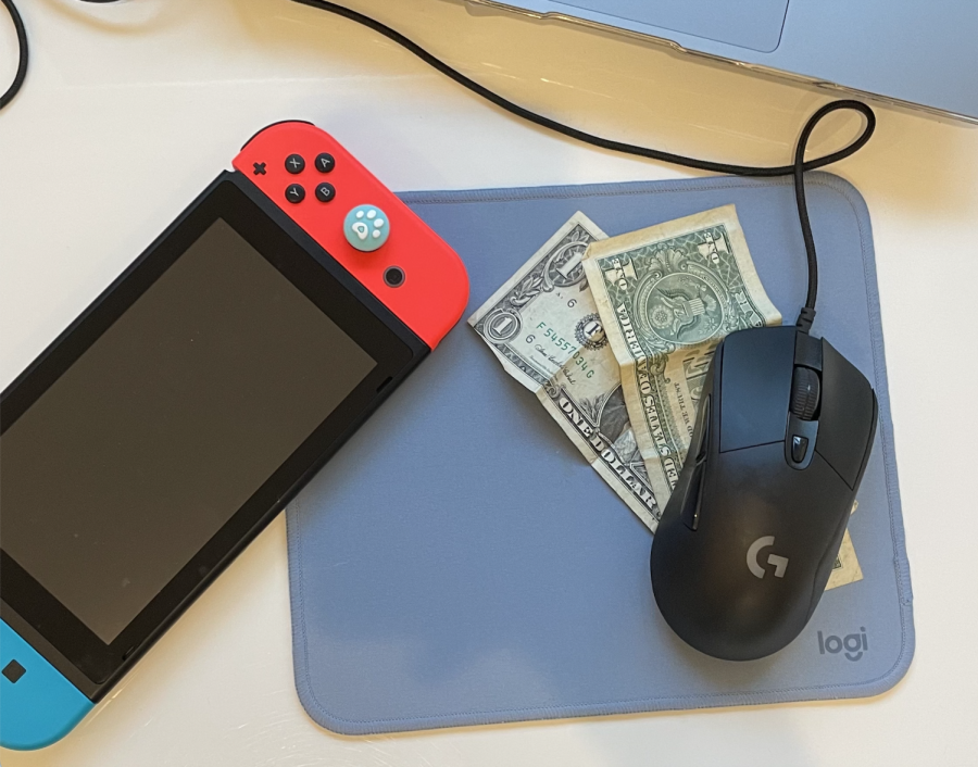 Image displays a Nintendo Switch alongside a gaming mouse and a few dollar bills. With the overwhelming prices of video games in the modern age, here are five wonderful games that you can play for free! Image credit to Paulina DePaulo.