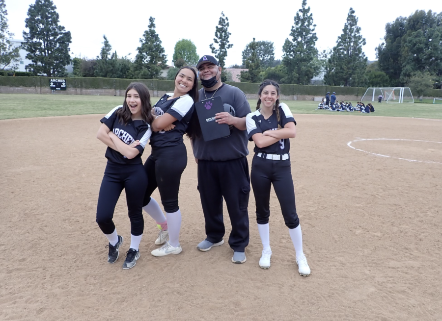 Francie Wallack (25), Malia Apor (24), Tony Flores and Maddie Beaubaire (25) pose together after their last game of the season. Coach Flores has been coaching the Archer varsity softball team for almost four years.