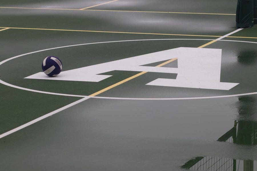 A volleyball rests on the Archer logo, which is painted on the sports court. The court can function as a playing space for volleyball, pickle ball and basketball and hosts Archer fitness classes.