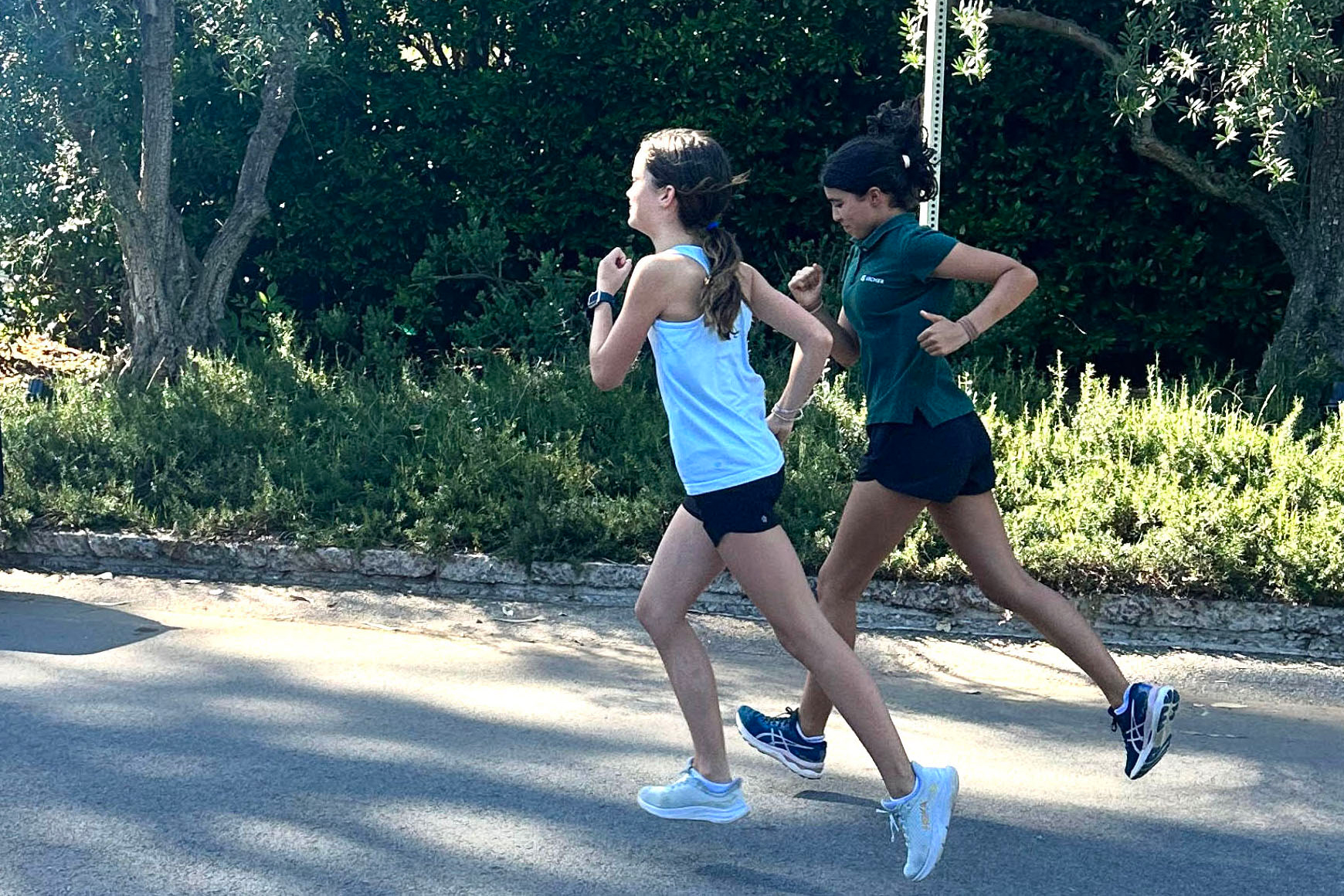Seventh graders Zoe Butler and Isabel Kromwyk run side by side on a sunny afternoon during cross country practice. Middle school cross country coach Kiaira Bostic said they are both determined athletes, and she looks forward to seeing them become stronger runners this season. 