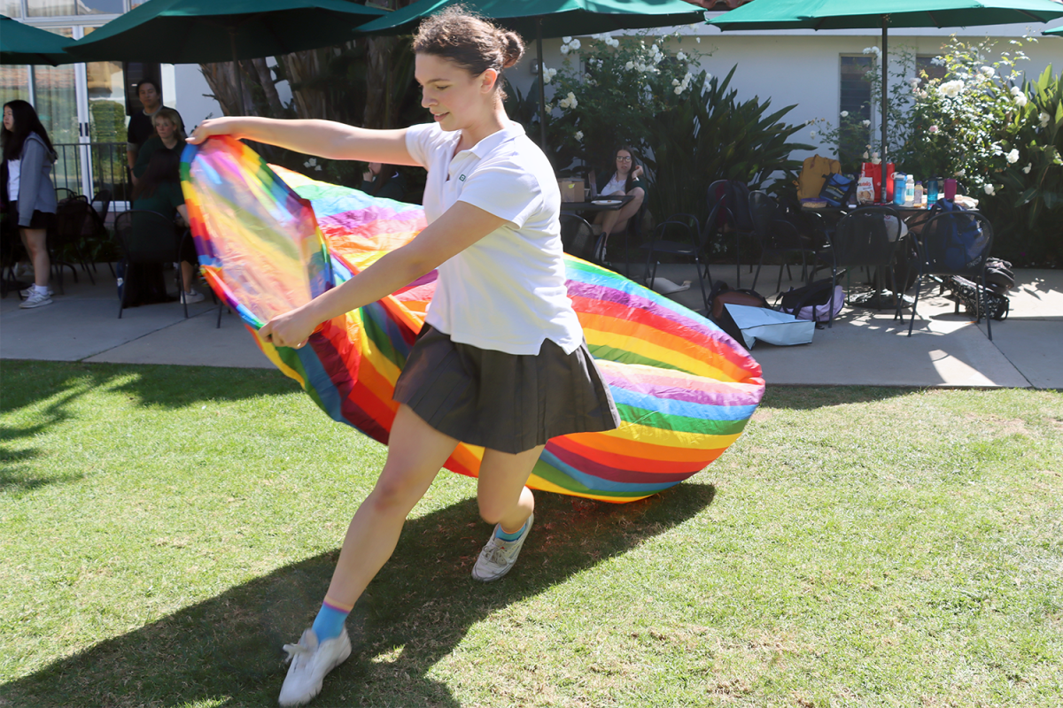 Gender Sexuality Alliance board member Bryce Collis (’25) runs around the courtyard, filling an inflatable pride-themed lounge chair with air during the National Coming Out Day celebration. For the celebration, which took place Thursday, Oct. 12, at lunch, GSA members set up tables with pride-themed tablecloths, candy and crafts.