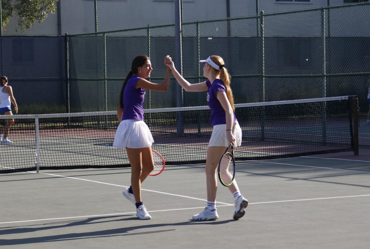Sophomores+Alex+Laffitte+and+Oona+Seppala+high-five+after+winning+a+doubles+match+on+Archer%E2%80%99s+home+courts%2C+Barrington+courts.+The+team+is+moving+into+the+Gold+Coast+league+next+year%2C+which+means+players+will+play+different+schools%2C+including+Brentwood%2C+Crossroads+and+Viewpoint.