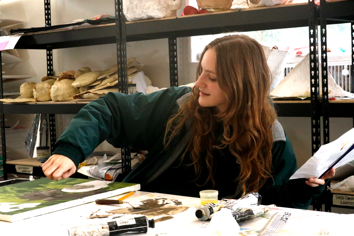 Olivia Boehm (‘26) works on a painting in the art studio. She started her own clothing business, Disregulation, in ninth grade, and it features her own artwork. “If Im going to do art, I might as well go full throttle and start my own business to really show how committed I am,” Boehm said.
