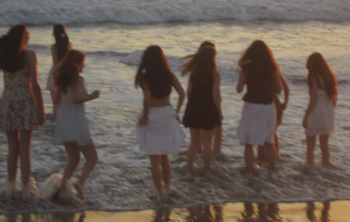 A group of friends dip their feet in the ocean at sunset. This photo was taken on a digital camera by Junior Rachel Chung. I also love the warmth and grain from [the camera] because it captures a very different feel compared to my [iPhone] camera. Junior Sofia Cianciolo said.
