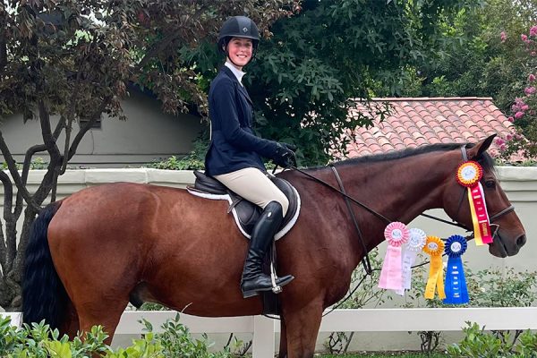 Lucia Macy (29) and Dealer, Macy’s trainer’s horse, show their winning ribbons after a horse show. As the equestrian team practices year-round, riders have trained at their respective barns and participated in other horse shows to prepare for the upcoming Interscholastic Equestrian Show in March. 