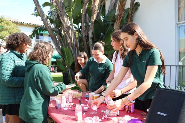 Junior Gabriella Specchierla pours sprinkles on a students cookie. Girls Empowering Girls hosted a Galentines day event Tuesday, Feb.13, where students decorated cookies and connected in the courtyard.