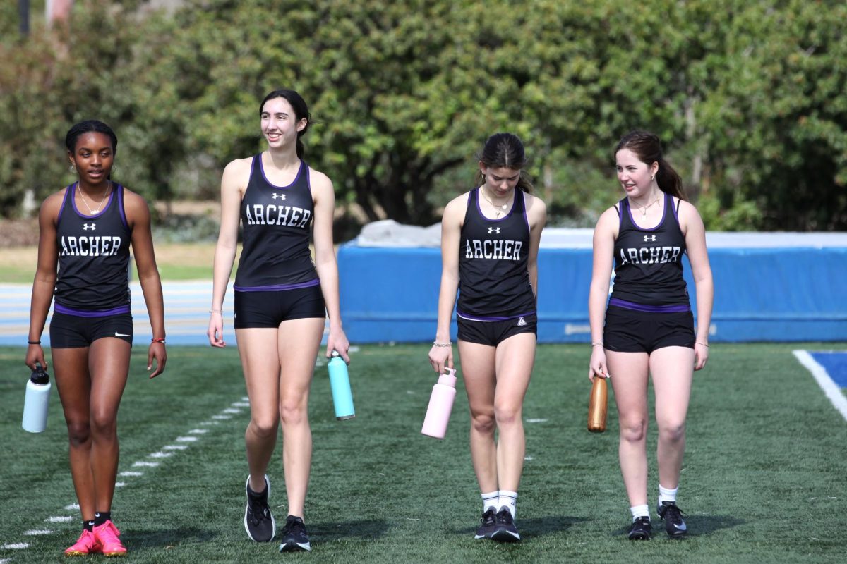 With their water bottles in hand, Chloe Hayden (’24), Maya Acutt (’25), Alex Bridwell (’27), Sophie Cousens (’27) walk across the West LA College field during their first track and field meet of the season. The team has faced challenges due to its size, but the runners have persevered through them and stayed committed, Athletics Assistant Madison Witt said. Photo by Archer Athletics.