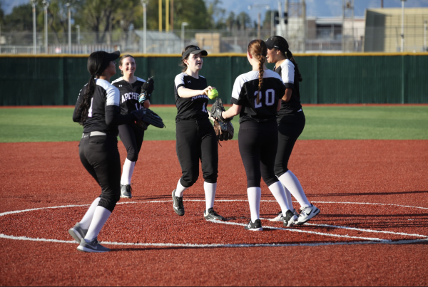 Players on the varsity softball team gather on a field. Junior Avalon Garland said all of the positions, ranging from the pitcher to basemen, have to work together to create a strong team. Photo by Archer Athletics.