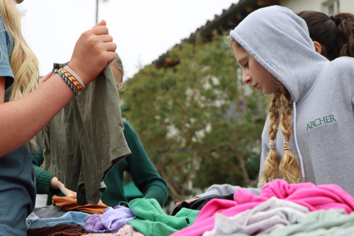 Lilly Swigert (30) browses through secondhand clothing items at the clothing swap, which allowed students to trade pieces with one another to promote sustainable consumer habits. The Archer Council for Sustainability organized the Earth Day celebration Monday, April 22, in partnership with the Artemis Center.