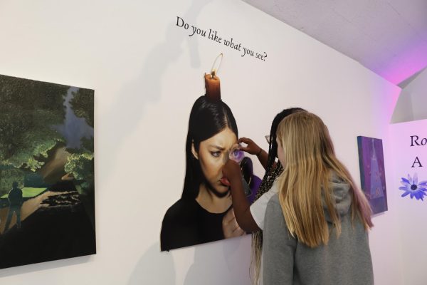 Serenity Jones (26) and Alice Rifenbark (28) interact with senior Sadie Longs artwork. Long and Chloe Resnick (24) opened their senior show, Roots & Reflections: A Surreal Look at Beginnings, in the Eastern Star Gallery Wednesday, April 10.