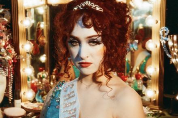 Chappell Roan stands in front of a vanity with a full face of makeup on and prom-like outfit for her album cover. Roan described her look in a Rolling Stone article as her own version of drag. Photo Source: Image from Official Chappell Roan site. 