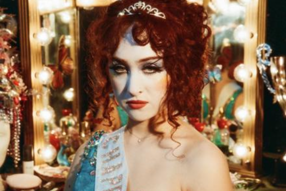 Chappell Roan stands in front of a vanity with a full face of makeup on and prom-like outfit for her album cover. Roan described her look in a Rolling Stone article as her own version of drag. Photo Source: Image from Official Chapell Roan site. 