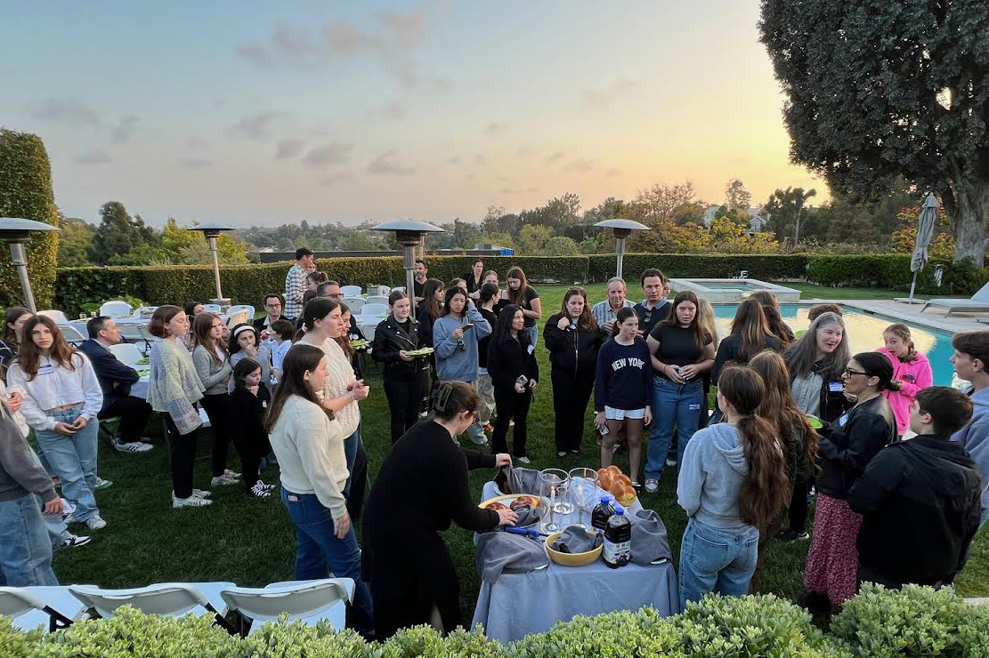 Tenth grade students lead the Shabbat prayers as attendees gather around and join in prayer. The Shabbat prayers consist of candle lighting, blessing the wine or juice and blessing the challah. Photo by Mia Alpert.