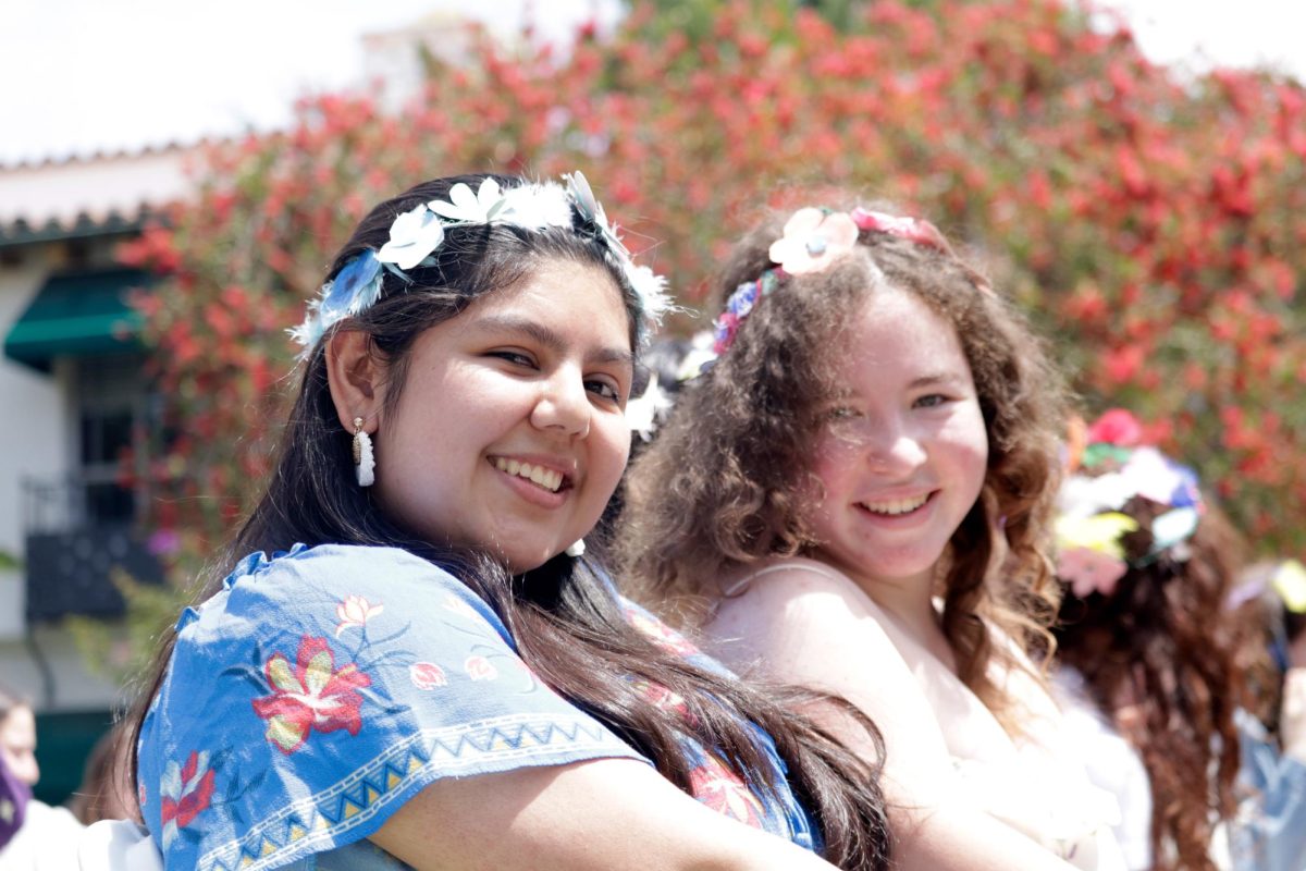 Sitting in the sun, seniors Maia Alvarez and Nina Sperling watch the Senior Tea Party. The tea party celebrated the Class of 2024s influence on student groups such as the Robotics team and Invent team. 