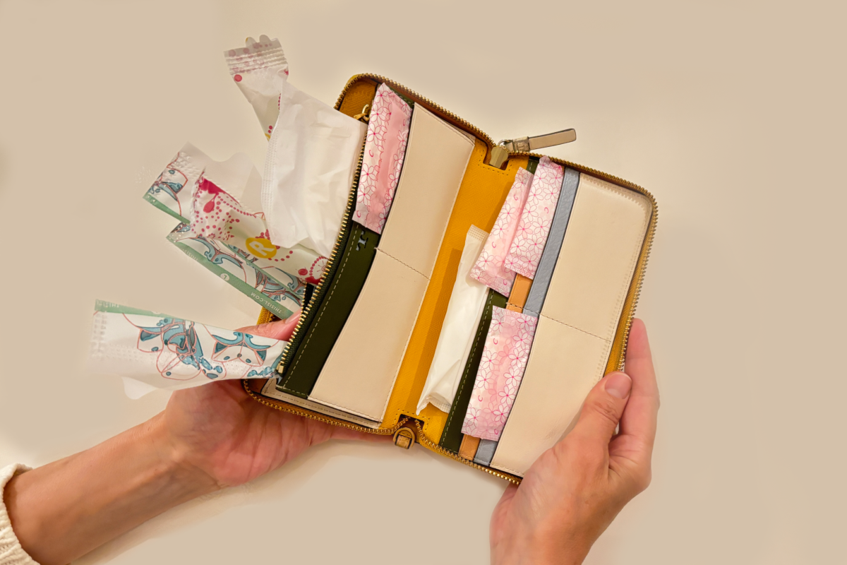 Menstrual products lie inside of a wallet, showing how costly these essential products can be. Although The Pink Tax affects menstrual products, it also impacts other everyday costs for women.