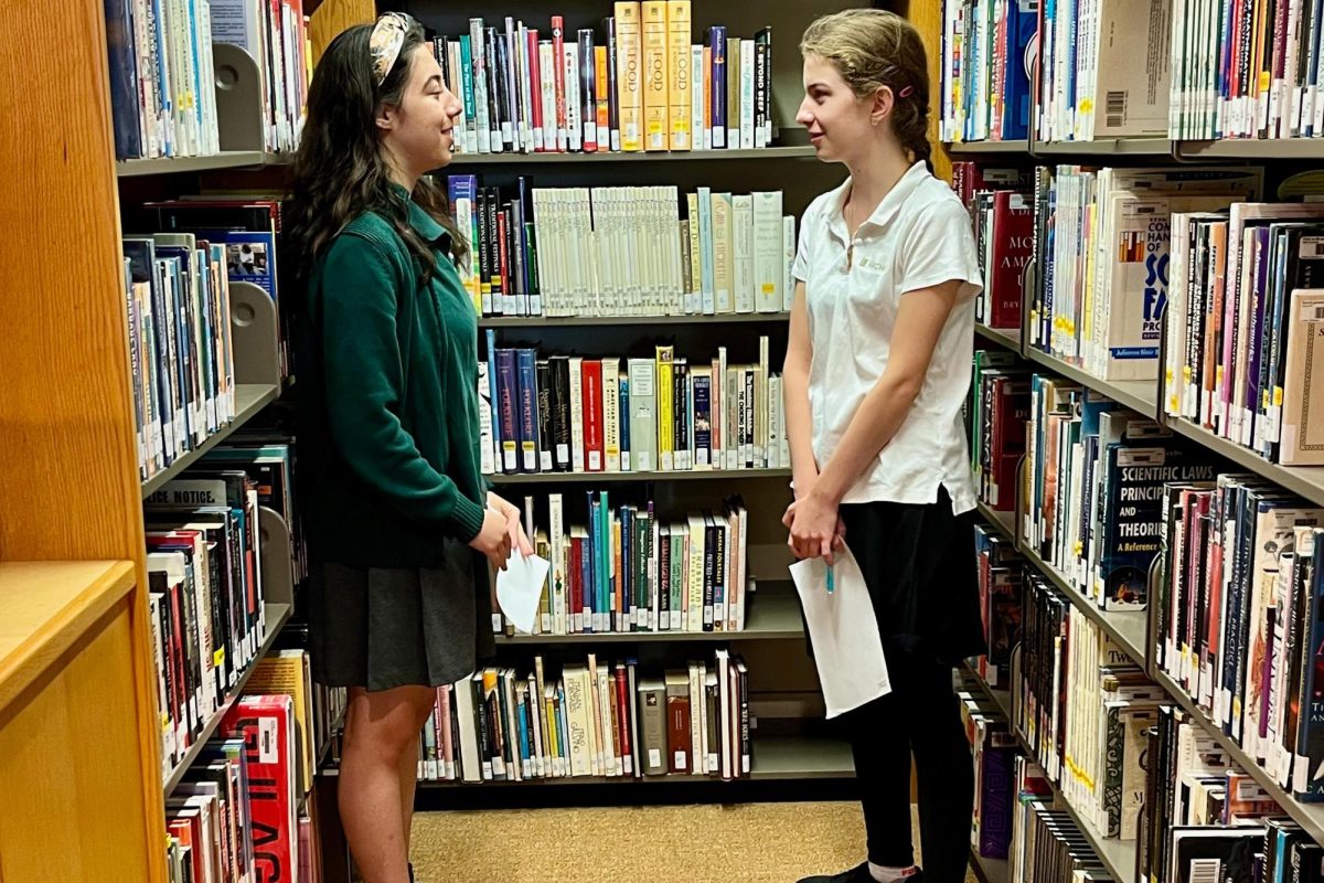 Juniors Vivianne Arnold and Lucy Kaplan recite their chosen poems in the library Tuesday, Sept. 17. In the 11th grade Advanced Study English classes, students were tasked with picking a poem that was meaningful to them. (Photo credit: Kathleen Keelty).