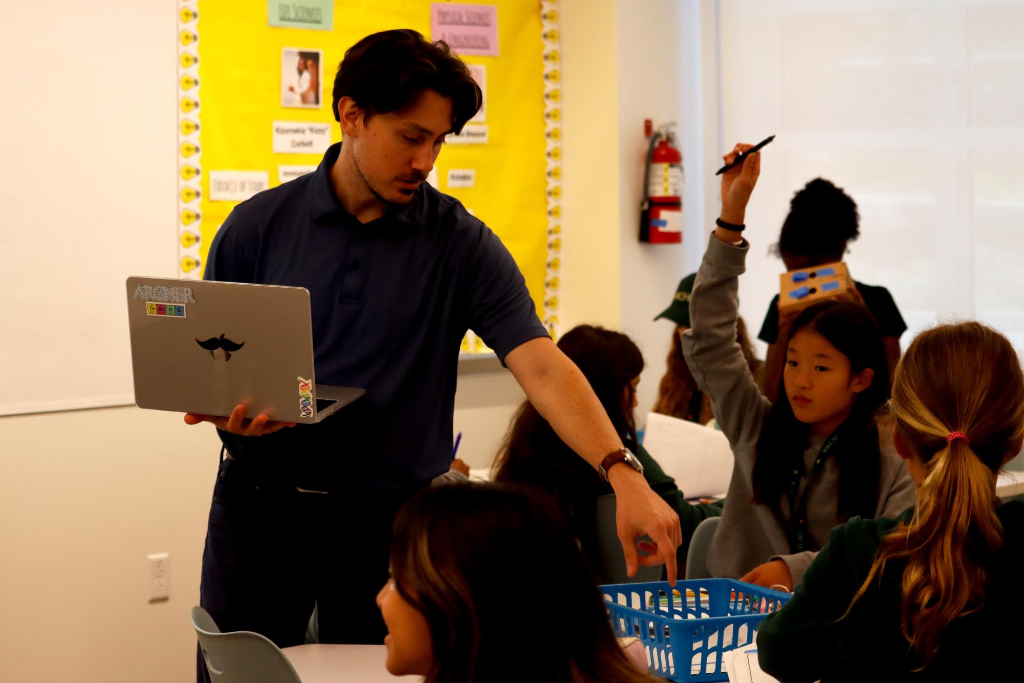 Science teacher Charlie Watts answers lab book questions during a class Sept. 24. Watts is a new science teacher for sixth and seventh grade at Archer and has a background in coding and technology. 