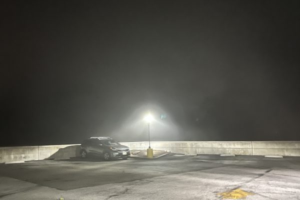 A streetlamp illuminates a car on the roof of a parking structure at night. This situation could be dangerous and would likely scare high school students, which is why we believe schools should teach self-defense. 